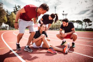 Group of athletes and trainers attending to an injured athlete on a running track