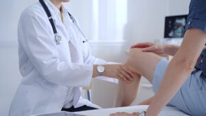 Doctor examining a patient's knee during a pre-synovectomy consultation.