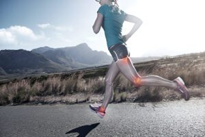 Runner in teal shirt on mountain trail with skeletal overlay showing knee joint impact points